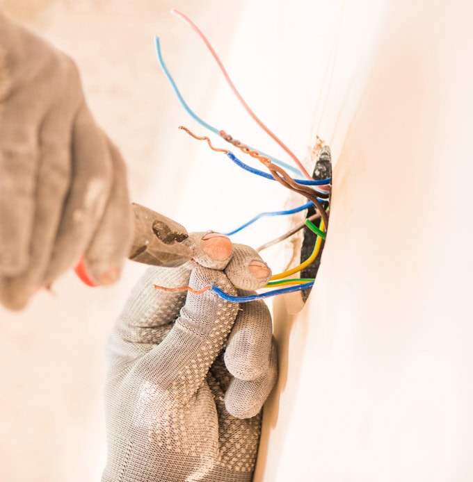 Gloved hand handling electrical wiring and meter Melbourne