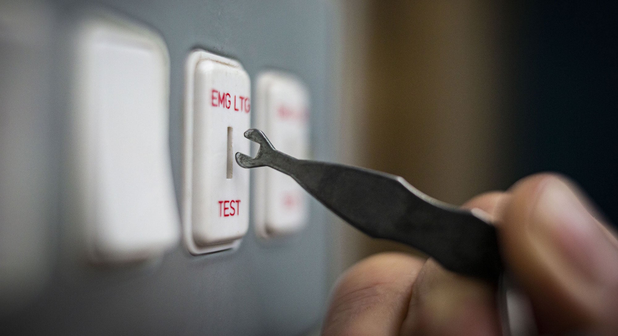 Technician conducting an emergency light test using specialized tools to ensure compliance and safety at a Melbourne property